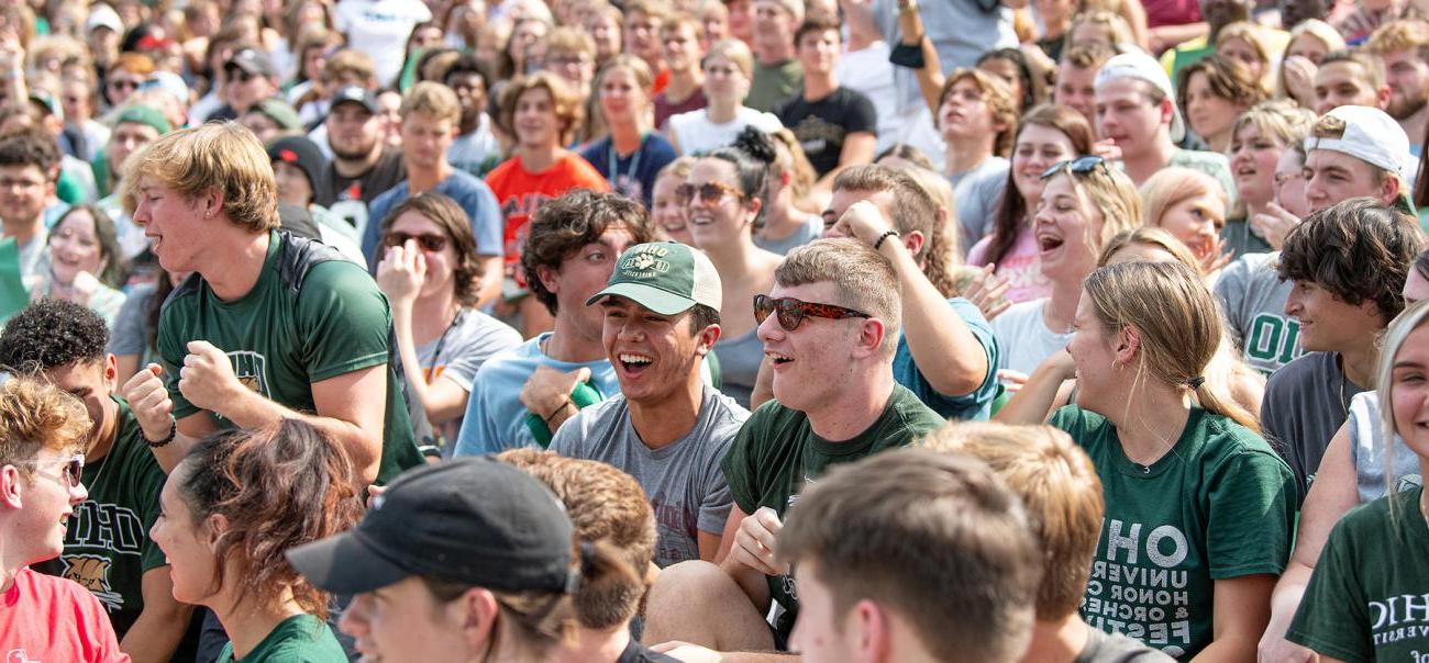 A group of Ohio University students laugh and smile together after sitting in the stands of a stadium